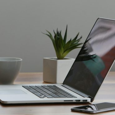 Free Minimalist home office desk with laptop, smartphone, and plant for a modern work environment. Stock Photo