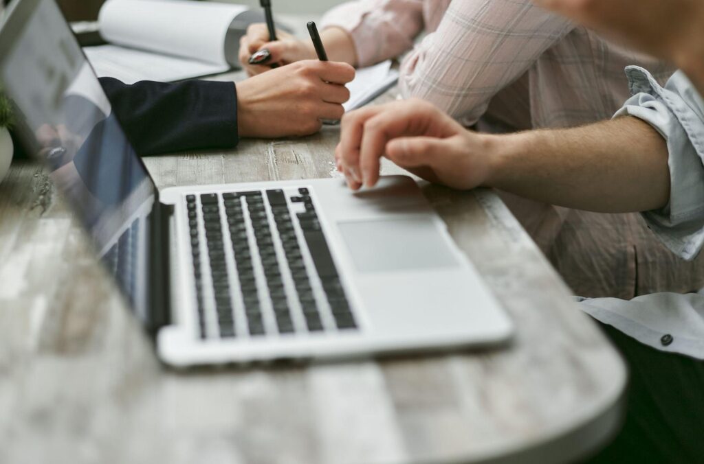 Two people working at a laptop on a shared table